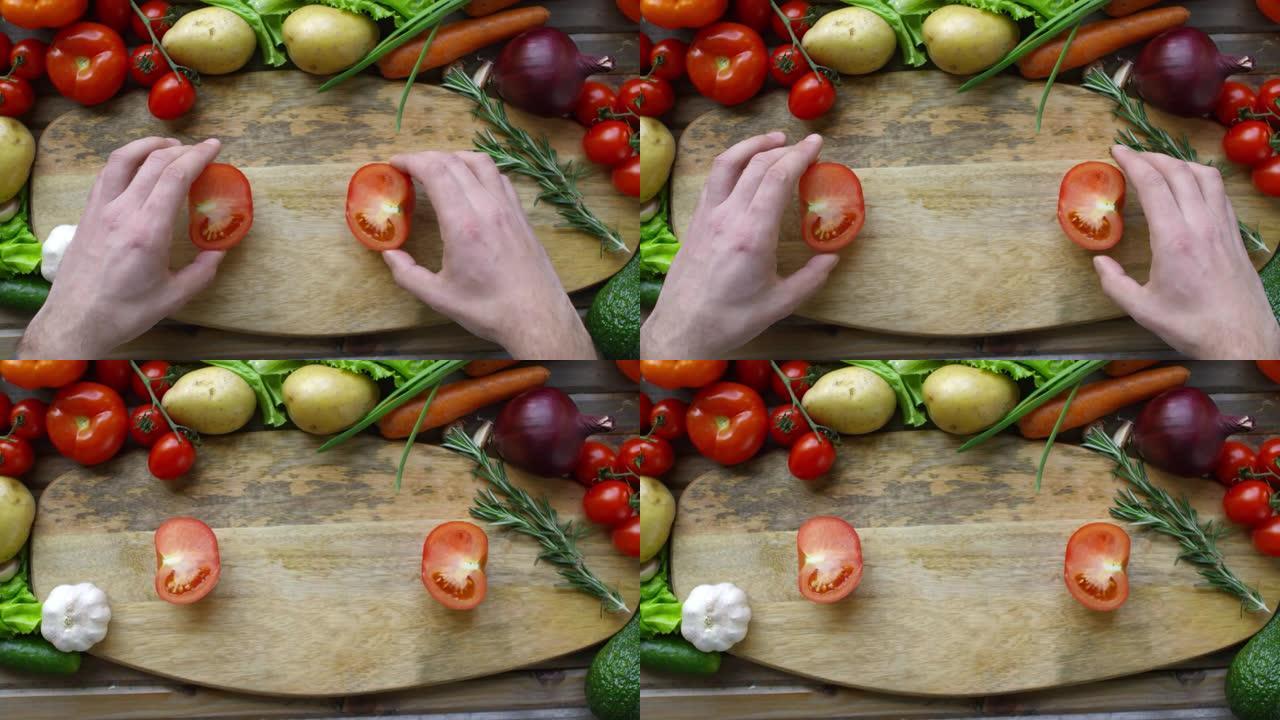 雄性手在砧板上分开两半番茄