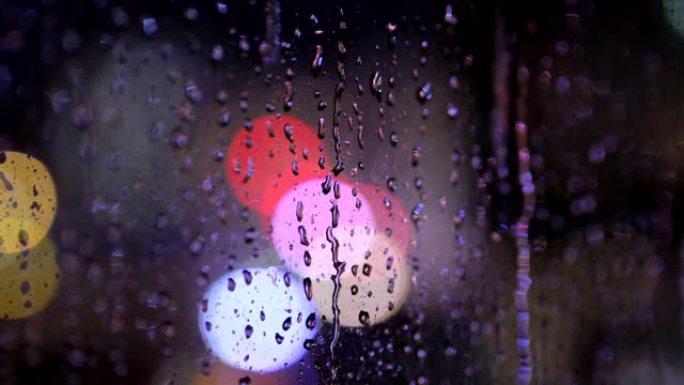 夜间从玻璃窗落下的雨滴