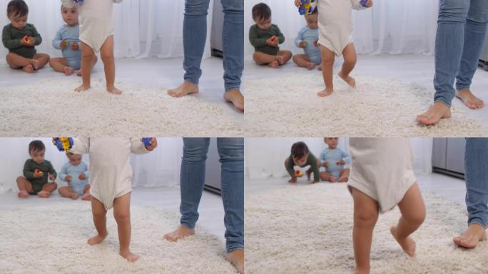 赤脚蹒跚学步的孩子在地毯上行走，三胞胎兄弟姐妹看着