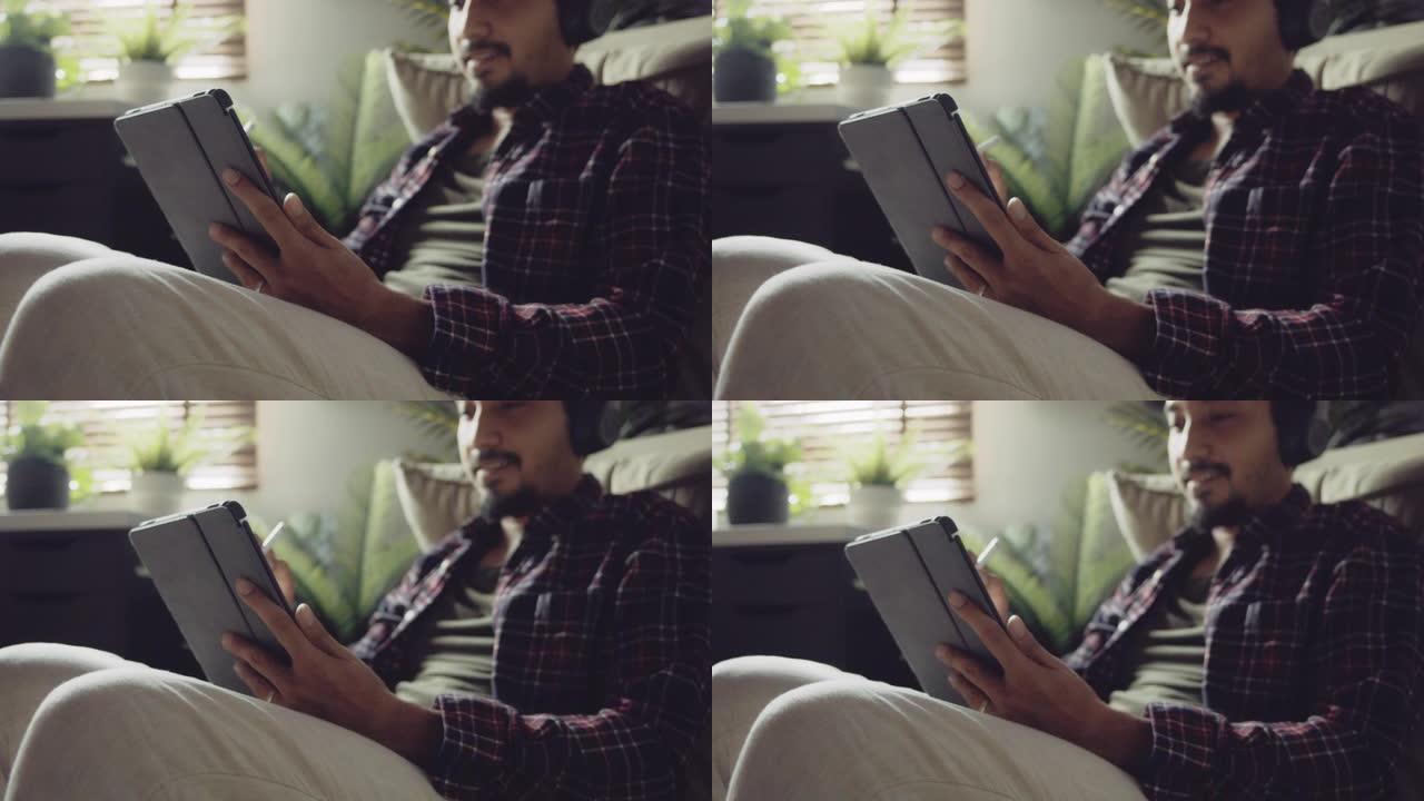 时髦的男人在家用平板电脑和手写笔听音乐和画画