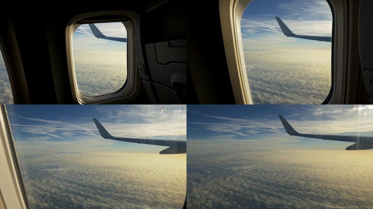 在飞行过程中从飞机舷窗拍摄视频。相机接近窗户，显示飞机如何在太阳照亮的软云面上方飞行。UHD