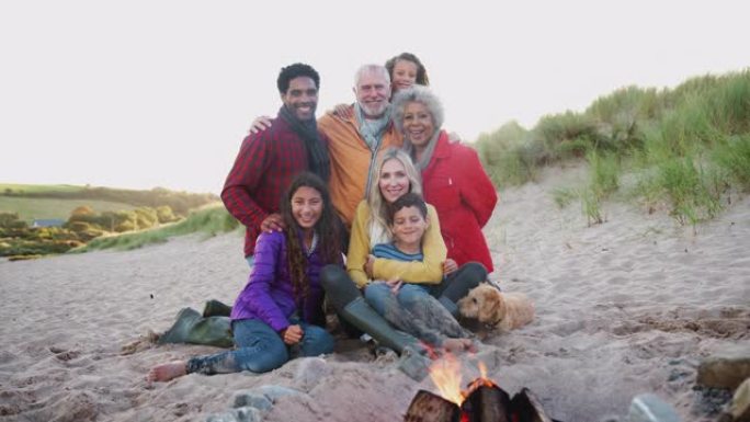 在冬季海滩上坐着火的多代家庭肖像-慢动作拍摄