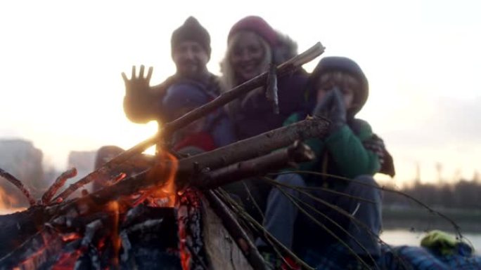 家庭在篝火晚会上热身。冬季乐趣。城市中的河边
