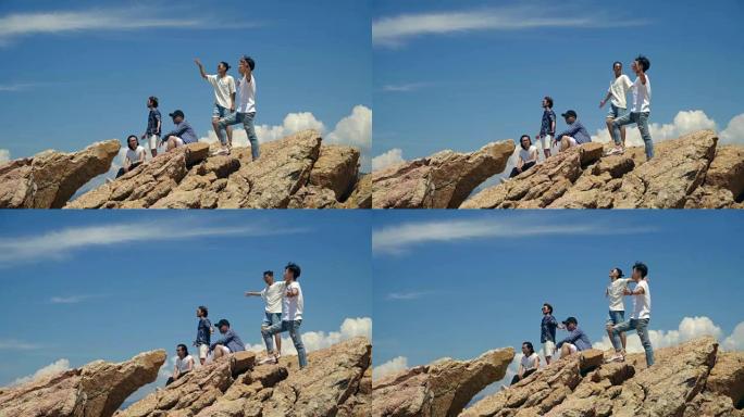 年轻的亚洲成年男子站在海边的岩石上
