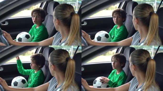 漂亮的小男孩和妈妈谈论他在车里的足球练习