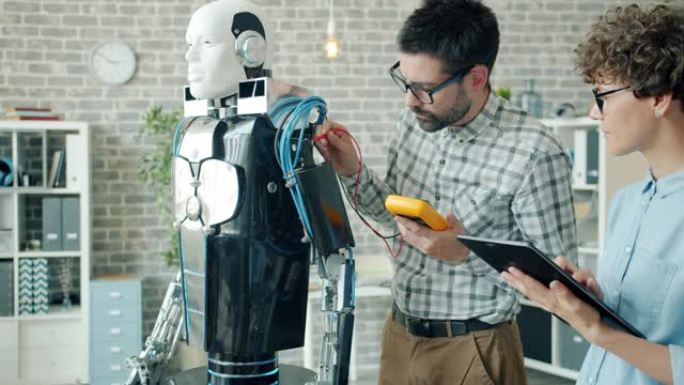 男性和女性开发人员使用在办公室工作的现代设备测试机器人