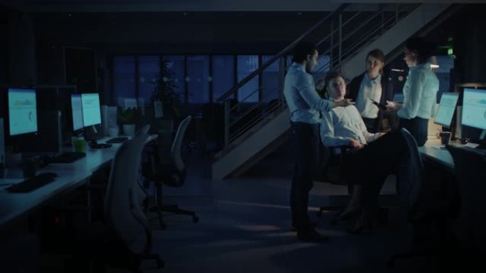 深夜在现代办公室: 由成功且雄心勃勃的商人和女商人组成的多元化团队在计算机上工作，进行讨论，寻找问题