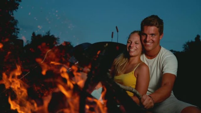 复制空间: 在浪漫的夏日夜晚，幸福的夫妻坐在篝火旁。