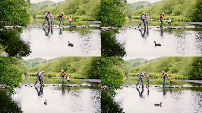 祖父母在英国湖区徒步旅行时帮助孙子过河的慢动作镜头