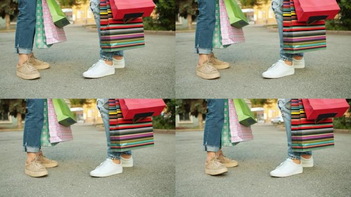 用彩色纸袋站在街上的妇女腿的低角度镜头