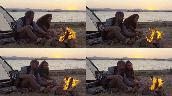 夫妇在海滩上做饭用火烧香肠野餐