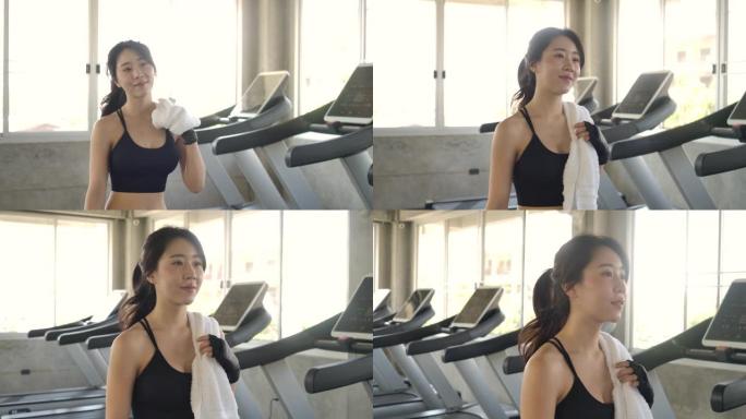 运动美丽的亚洲女子慢动作进入健身房的后续镜头。她很自信，拉着马尾辫。