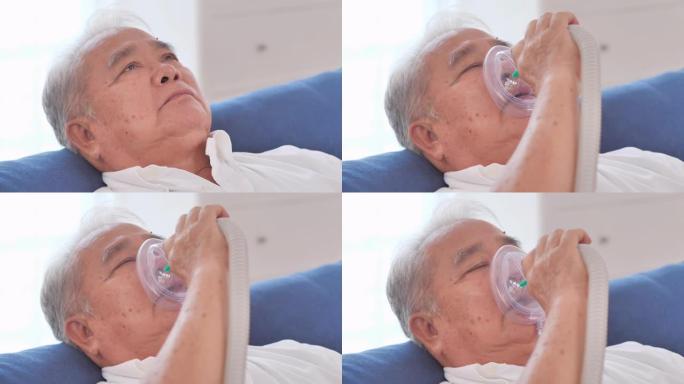 亚洲老爷爷在家中通过氧气面罩手持吸入器面罩。高级健康技术，医疗，护理，退休，药物保健，日常哮喘护理