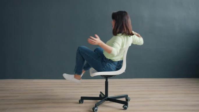 无忧无虑的女士在工作室的椅子上旋转，享受有趣的活动