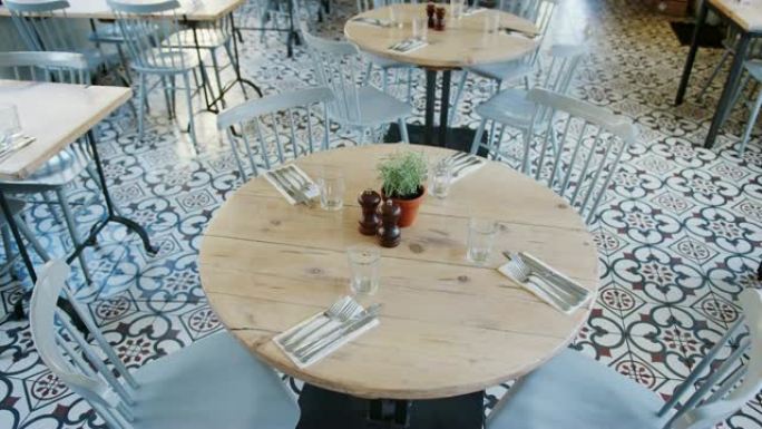 带瓷砖地板和特色窗户和石墙的餐厅的空桌椅的高架视图，手持