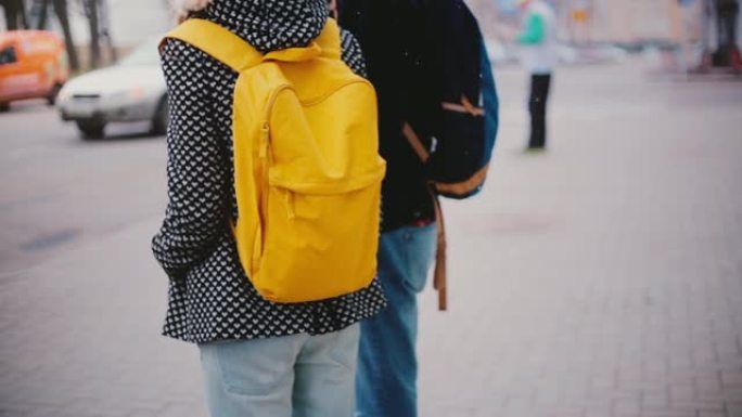 在寒冷的下雪的冬日里，当地男人和女人带着明亮的黄色背包站在一起的背景图。