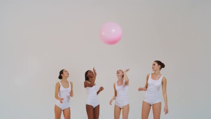 慢动作的美丽的年轻女性不同种族与完美的公司和苗条的身体在白色背心衬衫和短裤玩婴儿粉红色的气球