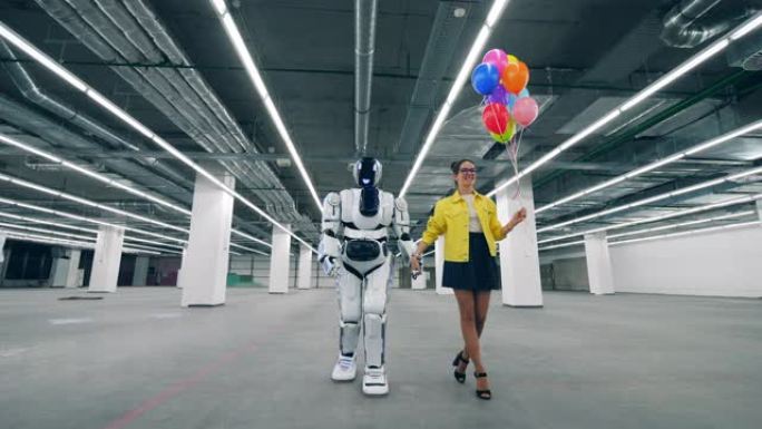 一位拿着气球的女士正带着一个半机械人沿着大厅散步