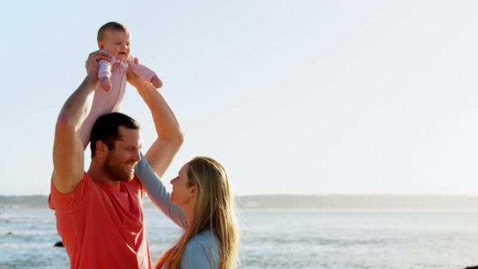 阳光灿烂的一天，白人成年父母在海滩上与婴儿在一起的侧视图4k