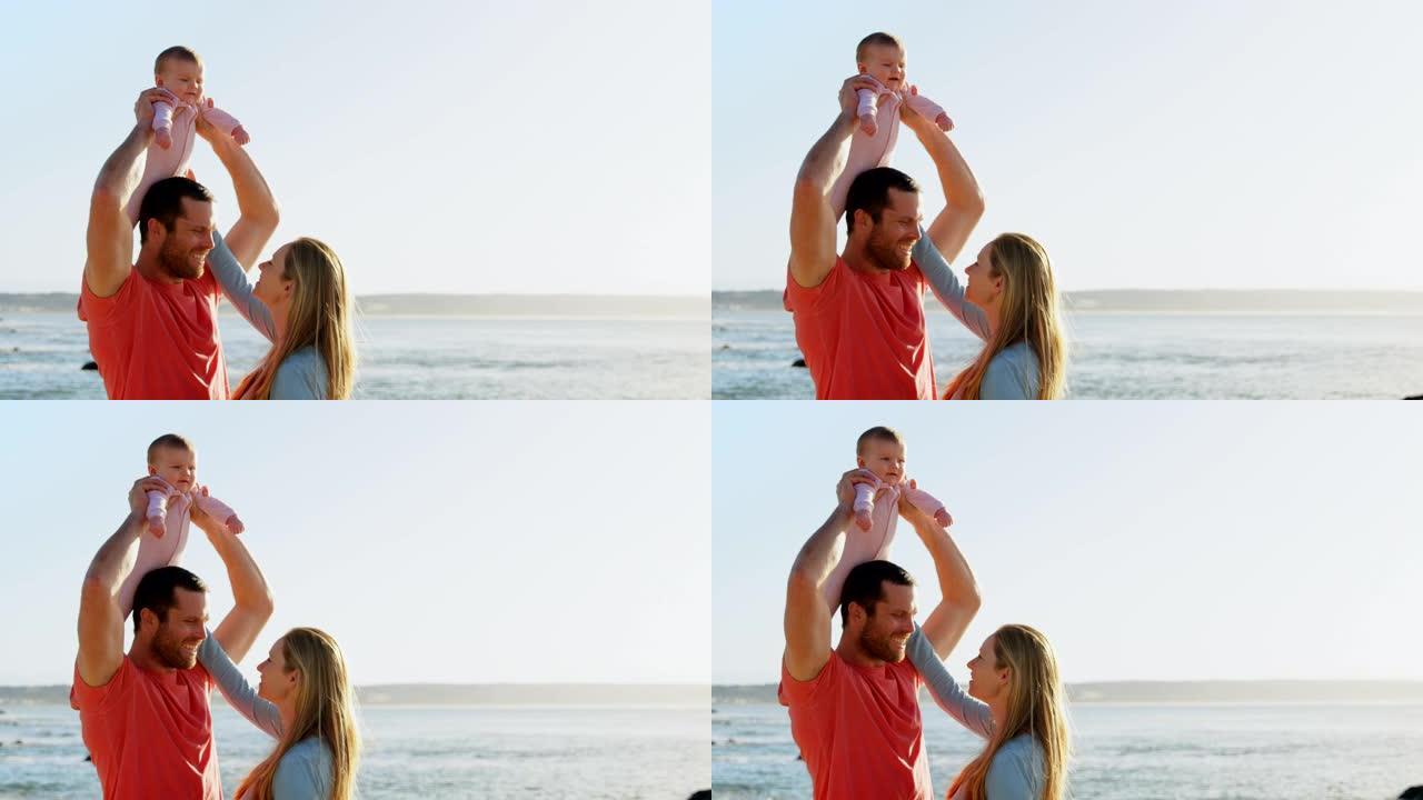 阳光灿烂的一天，白人成年父母在海滩上与婴儿在一起的侧视图4k