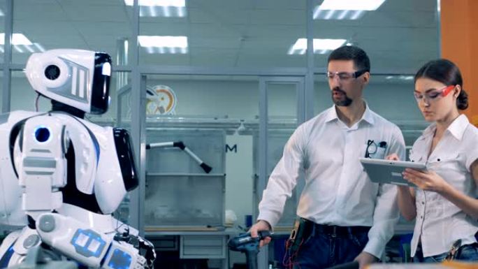 男人和女人检查机器人的工作。