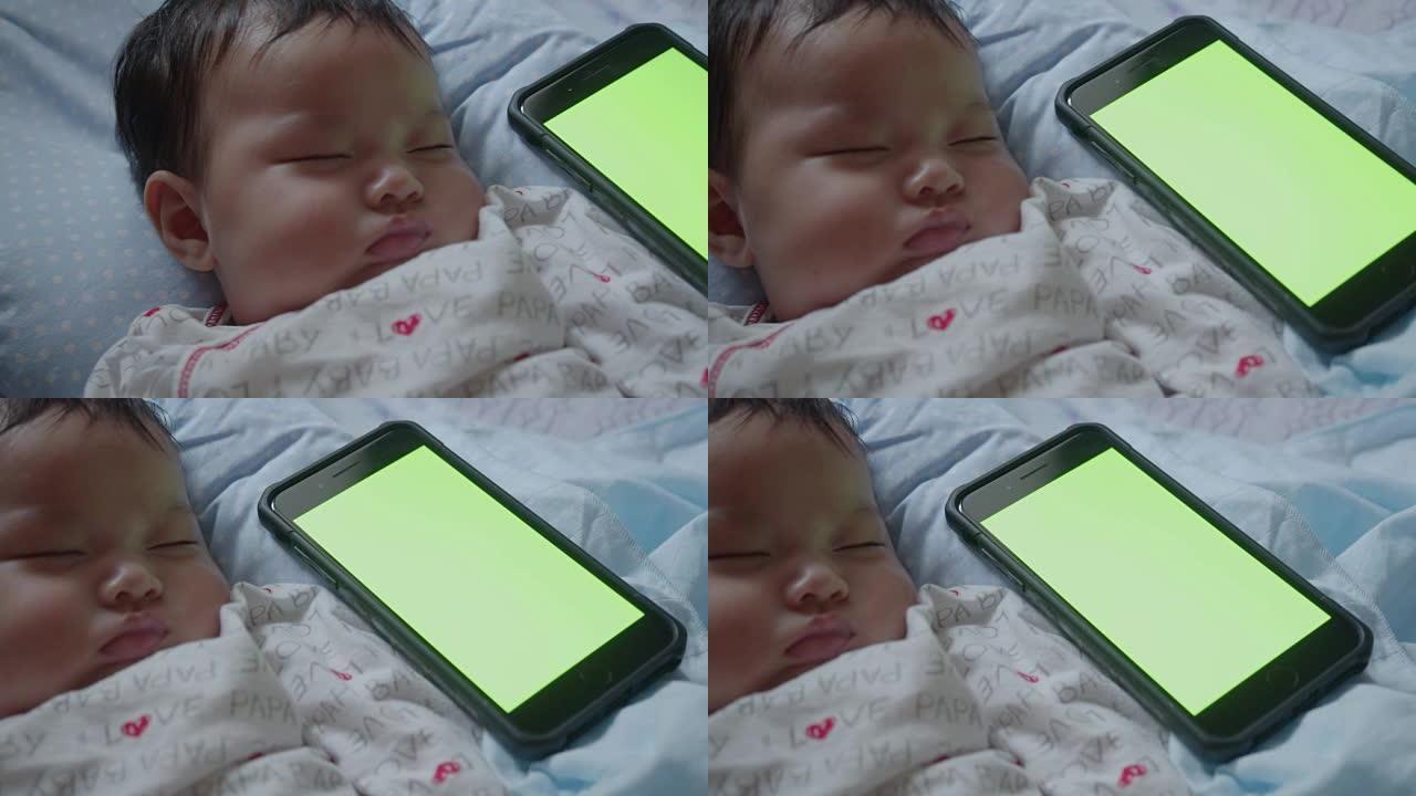 亚洲新生婴儿用绿屏智能手机睡觉
