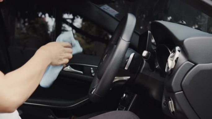 亚洲男子用超细纤维擦拭清洁汽车控制台