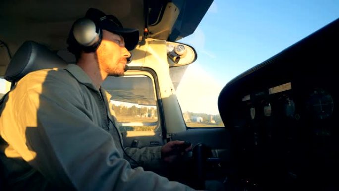 男性飞行员在驾驶舱内驾驶飞机，侧视图。