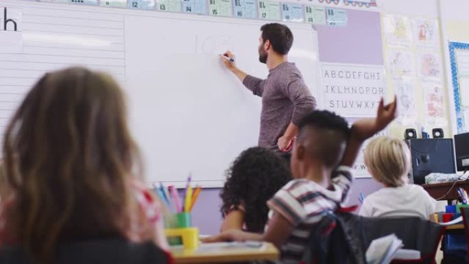 站在白板上的男老师在学校教室里给小学生上课