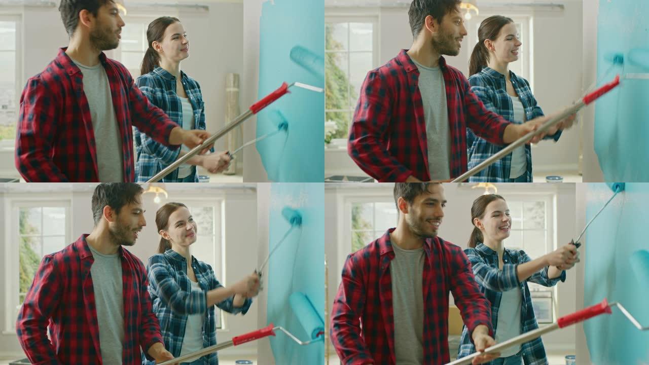 年轻漂亮的夫妇交谈并装饰他们的新公寓。丈夫和妻子正在用蘸有浅蓝色油漆的滚筒粉刷墙壁。家里的装修。