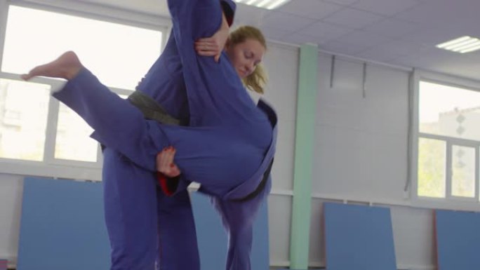 女子柔术运动员在拳击比赛中将男伴扔在垫子上
