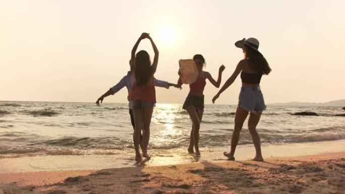 4k分辨率后视图组混合种族在日落时间在海滩上玩耍和跳舞。生活方式朋友旅行假期假期暑假概念。慢动作镜头