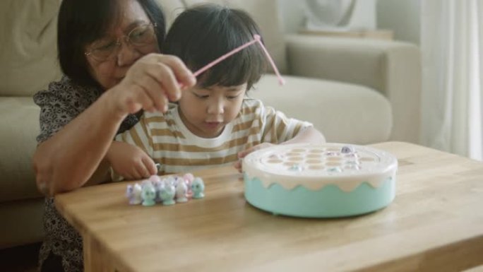 亚洲祖母和孙子在家里玩玩具。