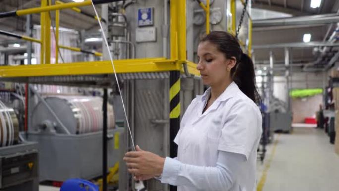 妇女在橡胶厂的一个车站检查胶带的生产