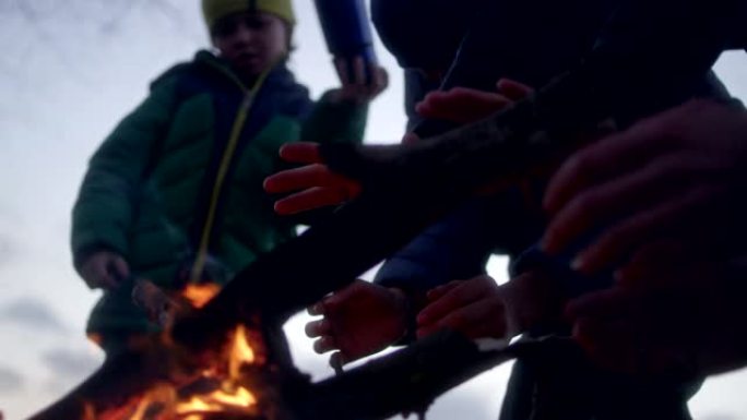 家庭在篝火中温暖双手。冬季乐趣。城市中的河边