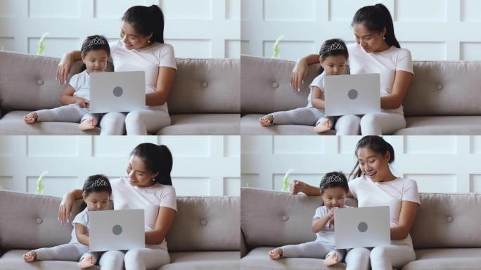 快乐的亚洲女儿学习笔记本电脑和妈妈一起看在线动画片