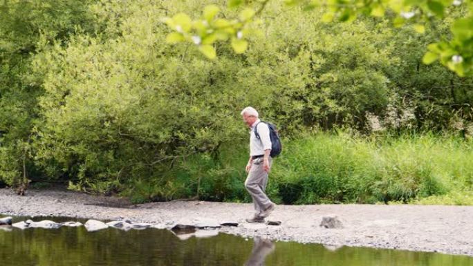 在英国湖区徒步旅行时，老人用垫脚石过河的慢动作镜头