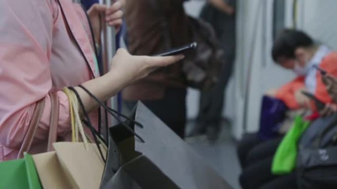 年轻女子在乘坐地铁时使用智能手机，慢动作