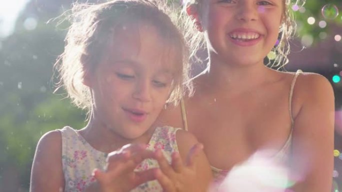 两个可爱的小女孩在房子外面玩肥皂泡的真实照片