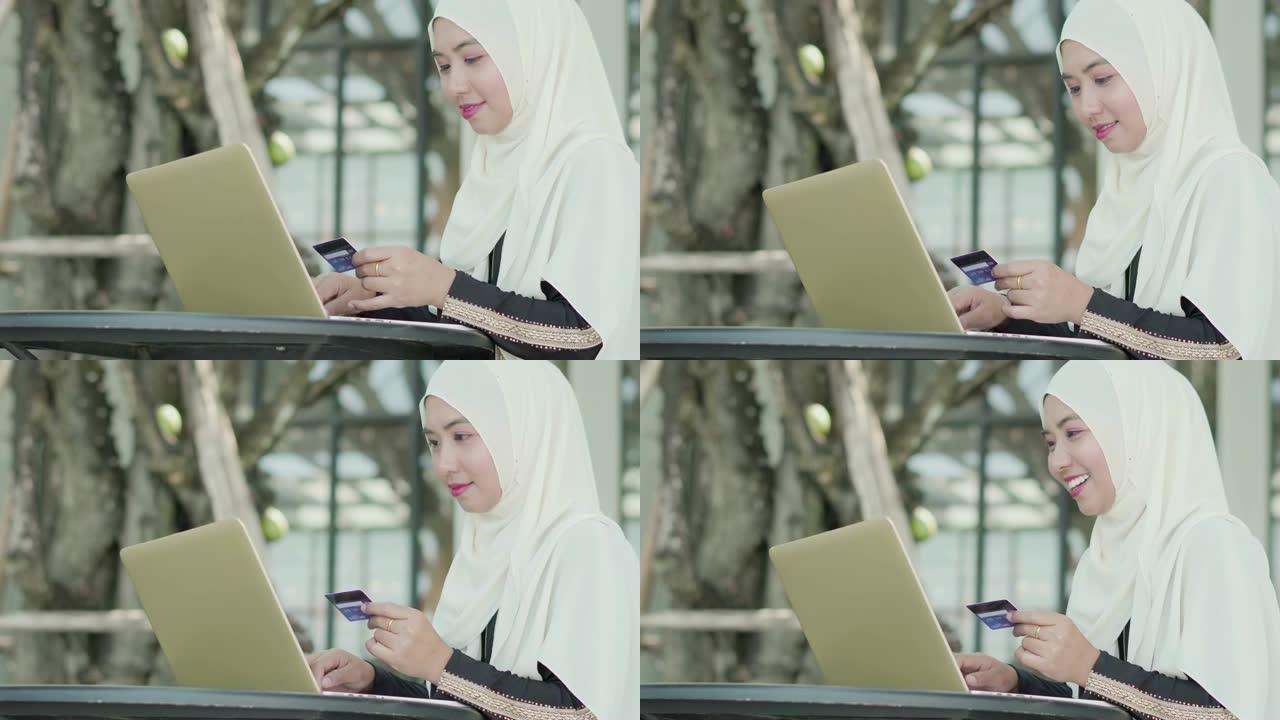 穆斯林妇女用信用卡和笔记本电脑在线购物。