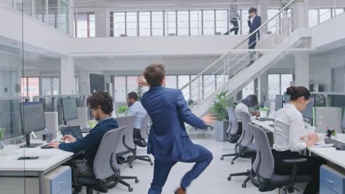 年轻开朗英俊的商务经理穿着西装，领带在办公室跳舞。在现代开放式办公室中，多元化且积极进取的商人在计算