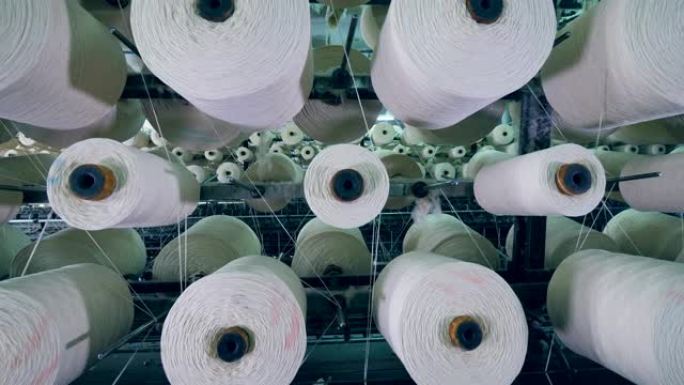 纺织厂机器工作时，白纱旋转的大卷轴。