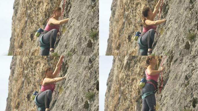 特写: 年轻的女攀岩者在阳光明媚的日子里攀登一个巨大的悬崖。