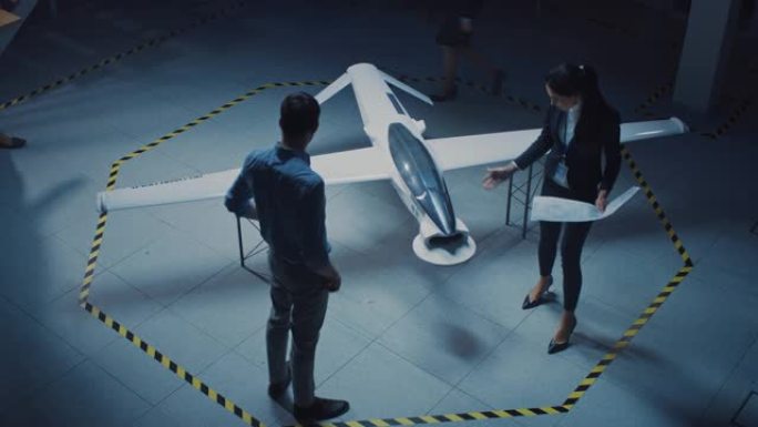航空航天工程师会议关于无人机/无人机原型的工作。穿着白大褂的航空专家交谈。带有监视或军用飞机的工业实