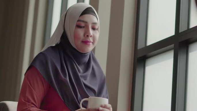穆斯林女孩在咖啡馆喝茶微笑的幸福。