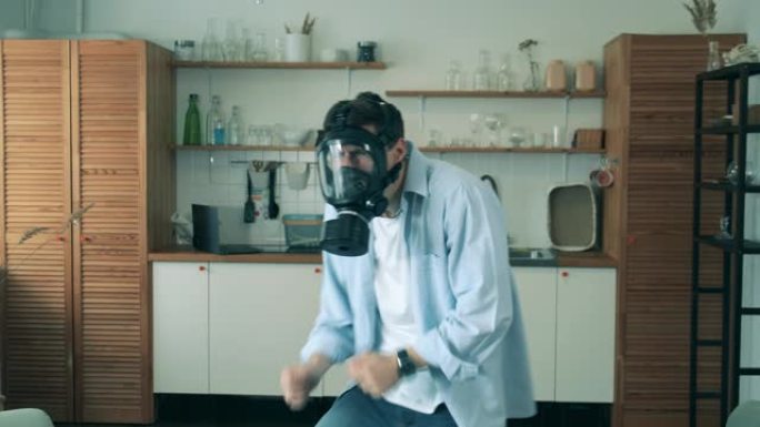 新型冠状病毒肺炎冠状病毒大流行期间，一名戴着危险品面具的男子正在家里跳舞。