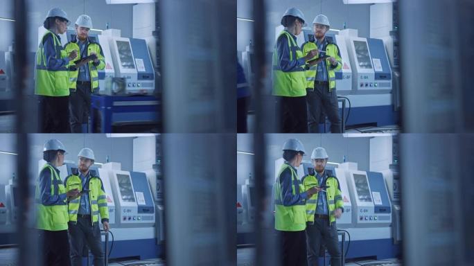 现代工厂: 女项目经理和男工程师站着穿着安全衣和安全帽，站在车间，说话，使用数字平板和监控数控机械装