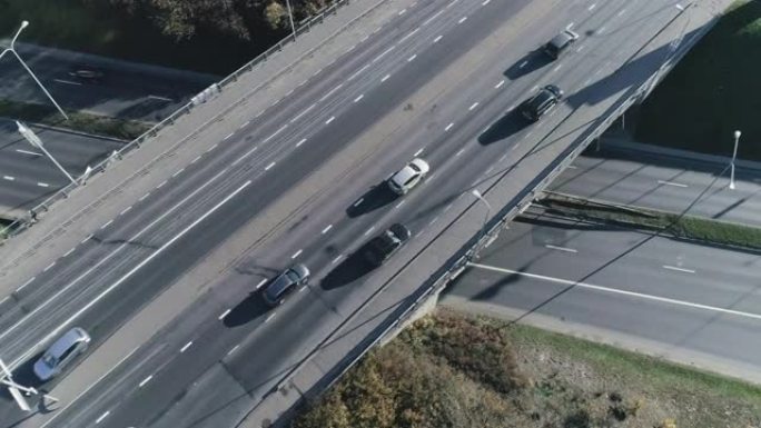 空中无人机镜头在城市桥梁交叉路口上方飞行，汽车交通适中。两层街道上的晴天。自上而下的视图。