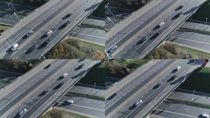 空中无人机镜头在城市桥梁交叉路口上方飞行，汽车交通适中。两层街道上的晴天。自上而下的视图。