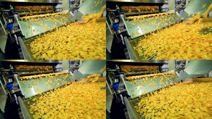 在一家工厂烹饪的黄色薯条，在食品生产输送机上移动。
